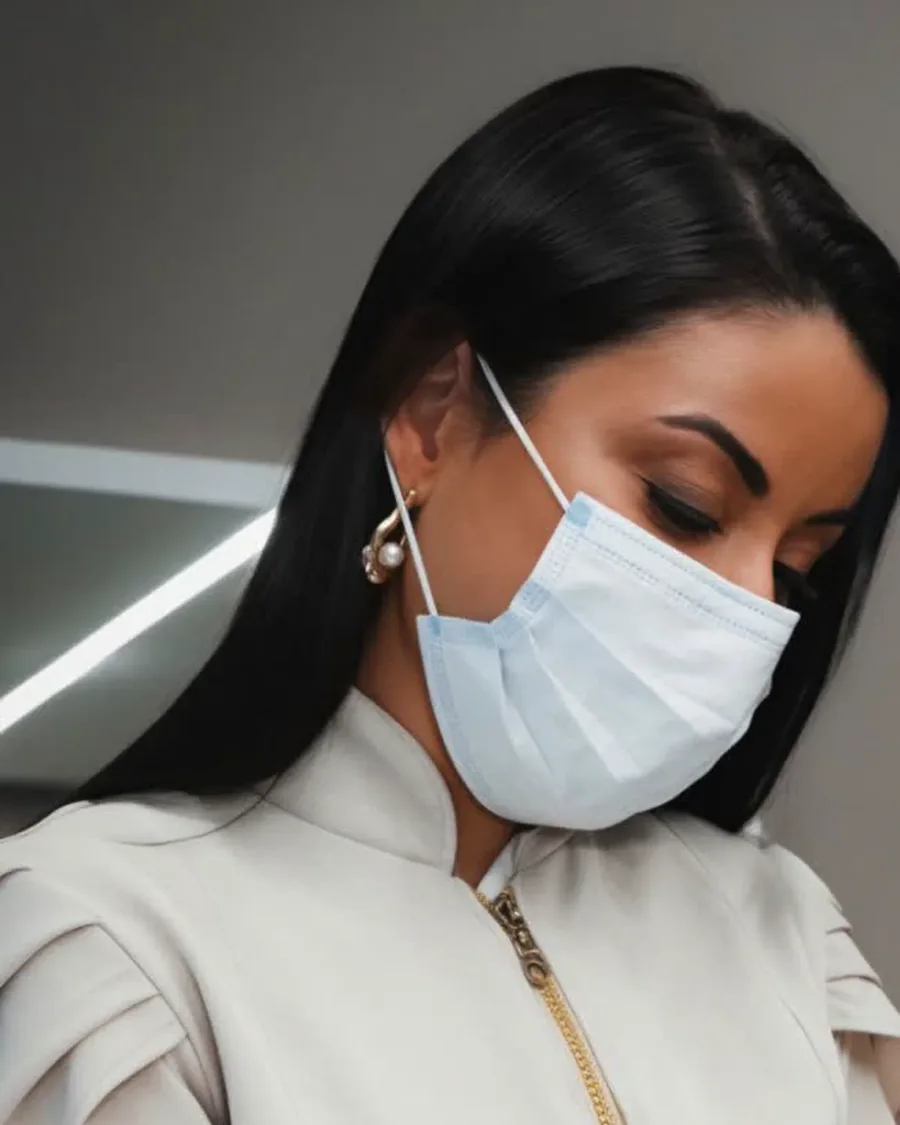 Dra. Jucielle Quintana durante atendimento, de jaleco premium com detalhe dourado, aplicando um procedimento facial
